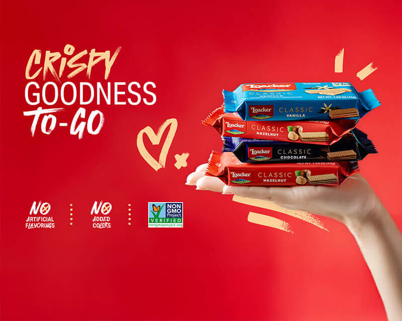 Hand holding Loacker wafers with 'Crispy Goodness To-Go' text on a red background