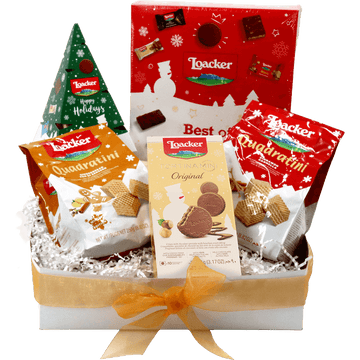 Loacker holiday gift box featuring Quadratini wafer cookies, Tortina Mini chocolates, festive Christmas packaging, white crinkle paper, and a gold ribbon bow.