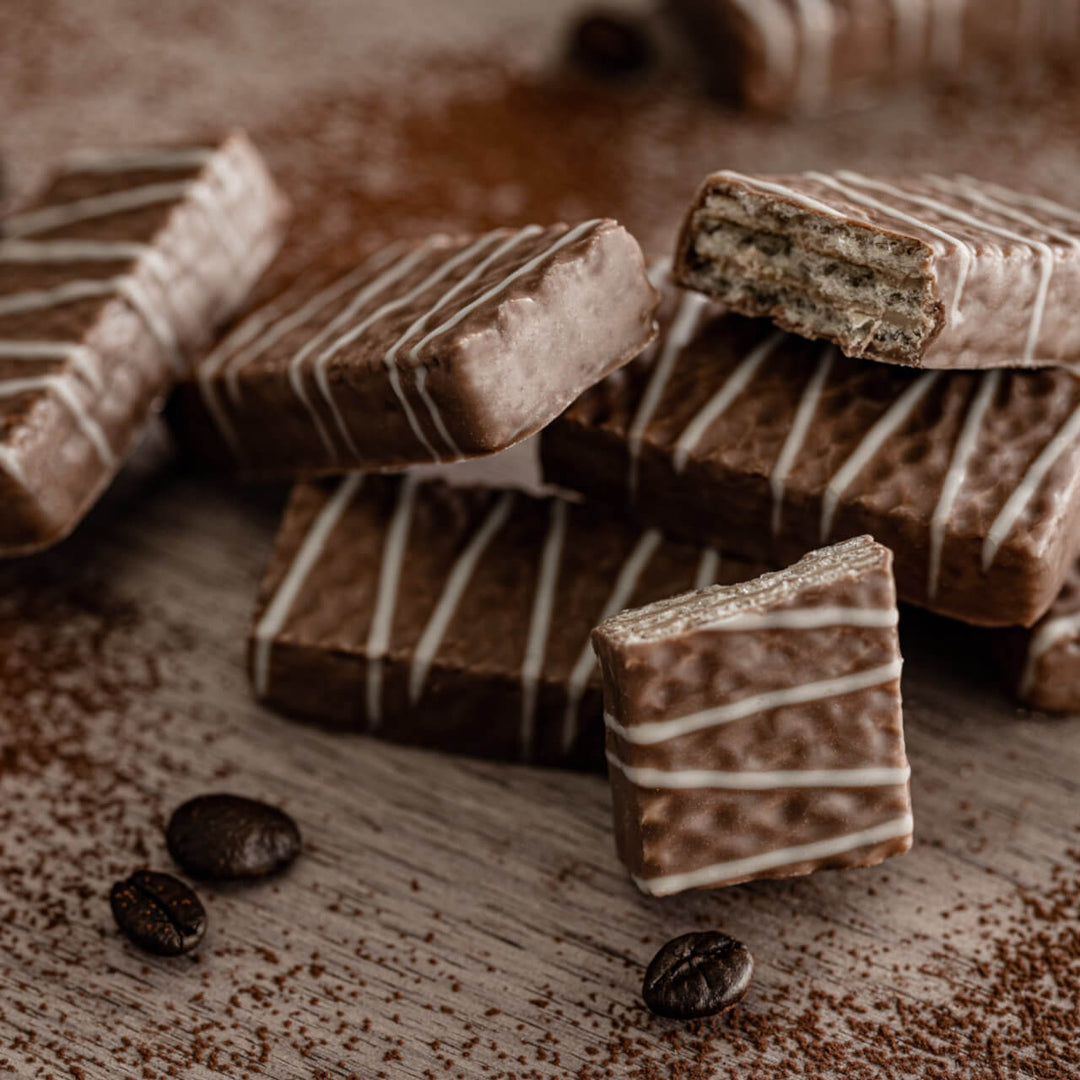 Chocolate bars with white drizzle on a wooden surface with coffee beans