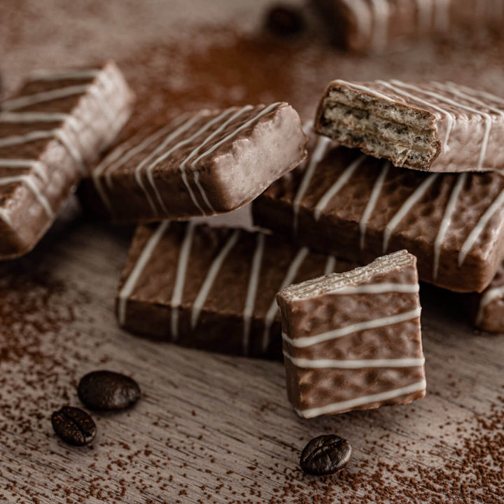 Chocolate bars with white drizzle on a wooden surface with coffee beans