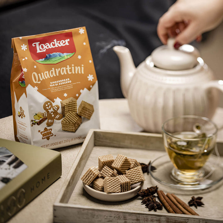 Quadratini Gingerbread, Creme-Filled Wafer Cookies, 8.82 oz. Bag with tea and tea pot, cinnamon sticks and anise next to it.